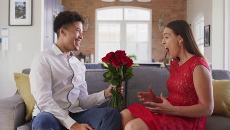 Happy-biracial-couple-celebrating-valentine's-day-giving-flowers-at-home