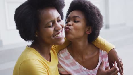 Happy-african-american-mother-and-daughter-embracing-and-kissing-in-garden