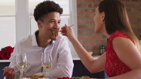 Happy-biracial-couple-having-valentine's-day-celebration-meal-at-home