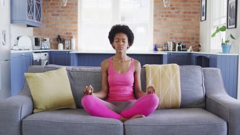 Una-Adolescente-Afroamericana-Relajada-Sentada-En-Un-Sofá-Haciendo-Yoga-Y-Meditando