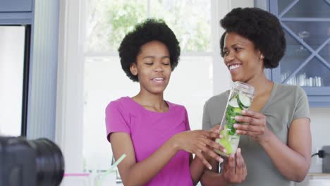 Glückliche-Afroamerikanische-Mutter-Und-Tochter-Bereiten-Gesunde-Getränke-Zu-Und-Machen-Videos-Mit-Der-Kamera