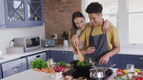 Glückliches-Gemischtrassiges-Paar,-Das-Zusammen-Kocht-Und-In-Der-Küche-Lacht