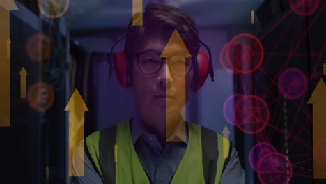 Animation-of-arrows-and-icons-over-asian-male-it-engineer-with-headphones-by-computer-server