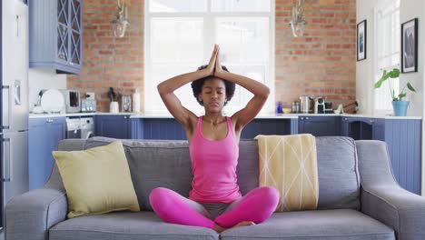 Entspanntes-Afroamerikanisches-Teenagermädchen,-Das-Auf-Dem-Sofa-Sitzt,-Yoga-Macht-Und-Meditiert