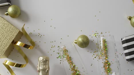 Animation-of-christmas-baubles-and-new-year's-eve-champagne-and-party-streamers