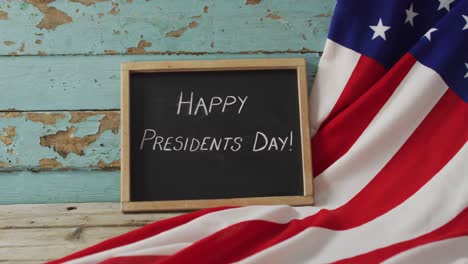 Happy-Presidents-Day-Text-Und-Amerikanische-Flagge-Mit-Sternen-Und-Streifen-Liegen-Auf-Einem-Holztisch