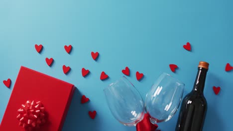 Present,-hearts-and-wine-glasses-on-blue-background-at-valentine's-day