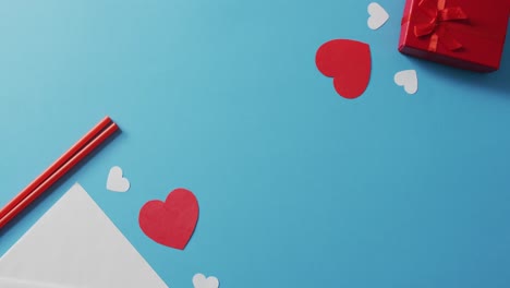 Straws-with-paper-hearts-and-present-on-blue-background-at-valentine's-day