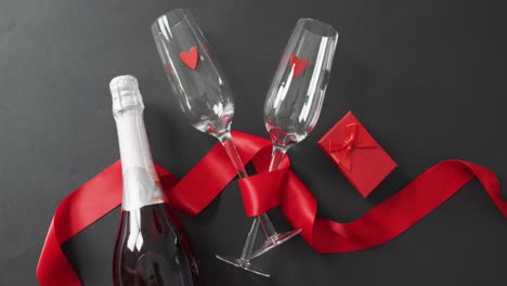 Champagne-glasses-and-bottle-with-present-and-red-ribbon-at-valentine's-day