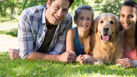 Glückliche-Kaukasische-Eltern-Und-Tochter-Liegen-Mit-Ihrem-Haustier-Golden-Retriever-Hund-Im-Park