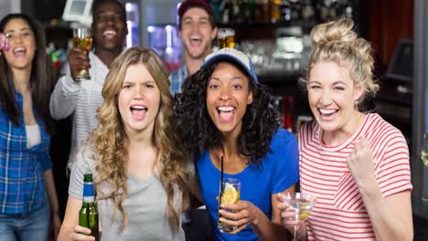 Happy-diverse-female-and-male-sport-fans-watching-game-at-bar,-cheering-and-drinking