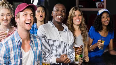 Happy-diverse-sport-fans-watching-game-at-bar,-drinking-and-smiling