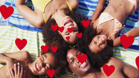 Animation-of-red-hearts-over-smiling-african-american-family-on-holiday-lying-on-beach-towels