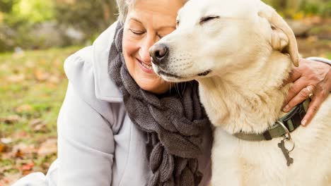 Happy-caucasian-senior-woman-embracing-golden-retriever-pet-dog-in-park