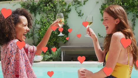 Animation-of-red-hearts-over-happy-diverse-female-friends-on-holiday-raising-glasses-by-pool