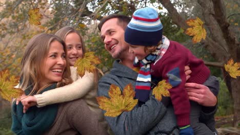 Animation-of-autumn-leaves-falling-over-happy-caucasian-family-in-park