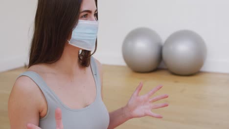 Caucasian-female-yoga-instructor-in-face-mask-talking-during-yoga-class