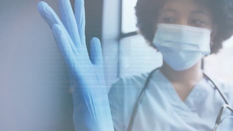 Animation-of-scanner-and-data-processing-over-female-doctor-in-face-mask-putting-on-surgical-gloves