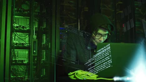 Animation-of-data-processing-over-asian-male-hacker-in-hoodie-with-laptop-by-computer-servers