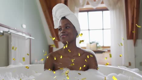 Animation-of-gold-confetti-falling-over-happy-african-american-woman-relaxing-in-bath-at-home