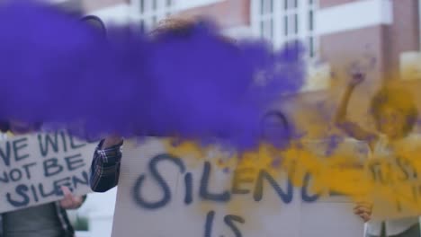 Animation-of-purple-and-yellow-smoke-trails-over-biracial-woman-using-megaphone-at-protest