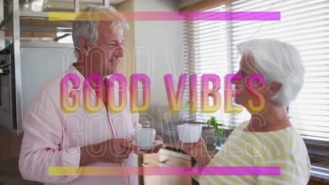 Animation-of-good-vibes-in-pink-over-happy-caucasian-senior-couple-having-coffee-talking-in-kitchen