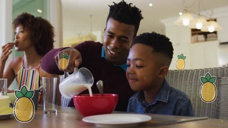 Animation-Von-Ananas-über-Glücklichen-Afroamerikanischen-Eltern-Und-Sohn,-Die-Zu-Hause-Frühstücken