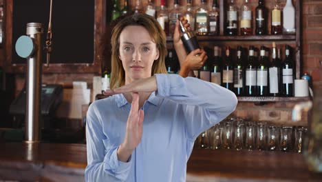 Animation-of-caucasian-woman-making-time-out-hand-sign,-over-barmaid-preparing-cocktail-at-bar
