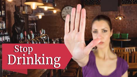 Animation-of-stop-drinking-text-with-caucasian-woman-making-stop-hand-sign,-over-bar-interior