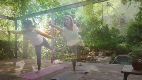 Animation-of-happy-asian-mother-and-daughter-practicing-yoga-over-trees