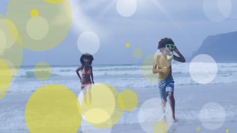 Animation-of-african-american-brother-and-sister-playing-at-beach-over-light-spots