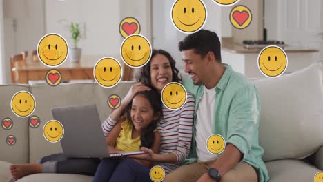 Animation-of-emoji-icons-over-happy-biracial-family-using-laptop
