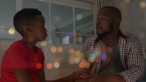 Animation-of-african-american-father-talking-with-son-over-city-at-night