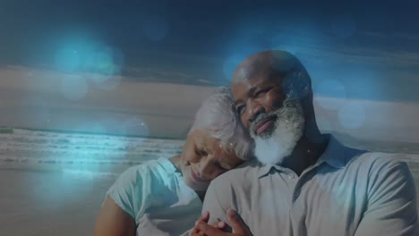 Animation-of-senior-african-american-couple-embracing-at-beach-over-light-spots