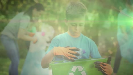 Animation-of-glowing-lights-over-boy-recycling-plastic-holding-green-recycling-box