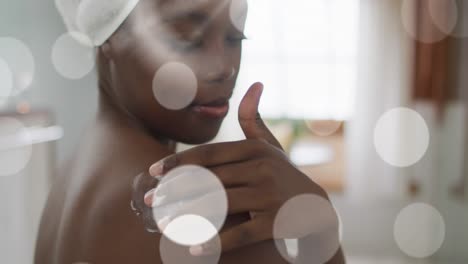 Animation-of-african-american-woman-using-cream-on-body-over-light-spots