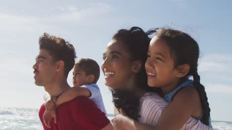 Glückliche-Hispanische-Eltern,-Die-Ihre-Kinder-Huckepack-Tragen-Und-Am-Strand-Spazieren-Gehen