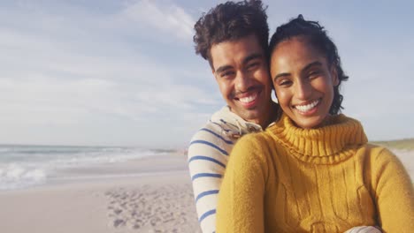 Porträt-Eines-Glücklichen-Hispanischen-Paares,-Das-Am-Strand-Steht-Und-Sich-Umarmt