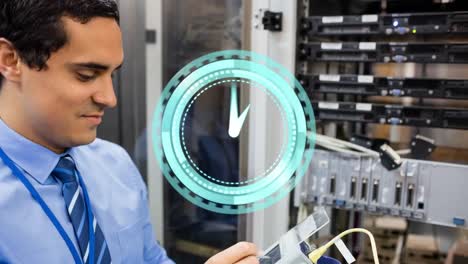 Animation-of-clock-moving-over-biracial-male-worker-inspecting-server-room