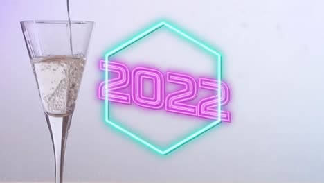 Animation-of-2022-neon-text-over-glass-of-champagne