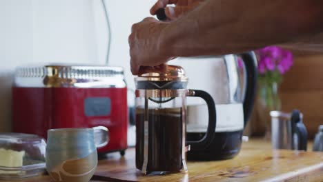 Hands-of-senior-caucasian-man-preparing-coffee-on-countertop-in-kitchen