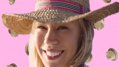 Animation-of-smiling-caucasian-woman-with-hat-over-falling-hats-on-pink-background