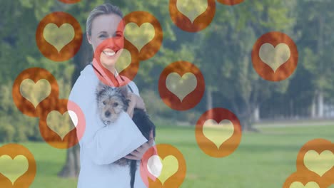 Animation-of-heart-icons-moving-over-smiling-female-vet-holding-dog