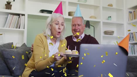 Animation-of-confetti-falling-over-senior-couple-in-party-hats-on-laptop-video-call