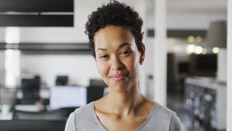 Portrait-of-biracial-businesswoman-smiling-and-standing-in-office