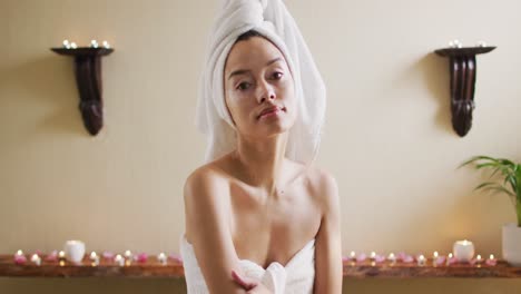 Portrait-of-relaxed-biracial-woman-in-robe-looking-at-camera-in-bathroom