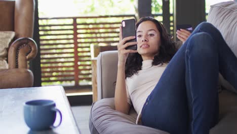 Entspannte-Gemischtrassige-Frau,-Die-Auf-Dem-Sofa-Liegt-Und-Ihr-Smartphone-Benutzt