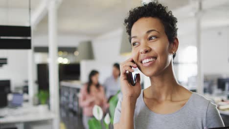 Portrait-of-happy-biracial-businesswoman-making-call-in-office