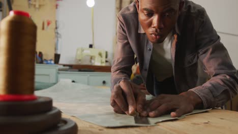 Fokussierter-Afroamerikanischer-Handwerker,-Der-In-Der-Lederwerkstatt-Ein-Stück-Leder-Schneidet