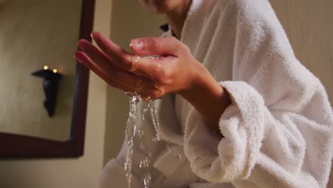 Hands-of-biracial-woman-preparing-bath,-checking-water-temperature